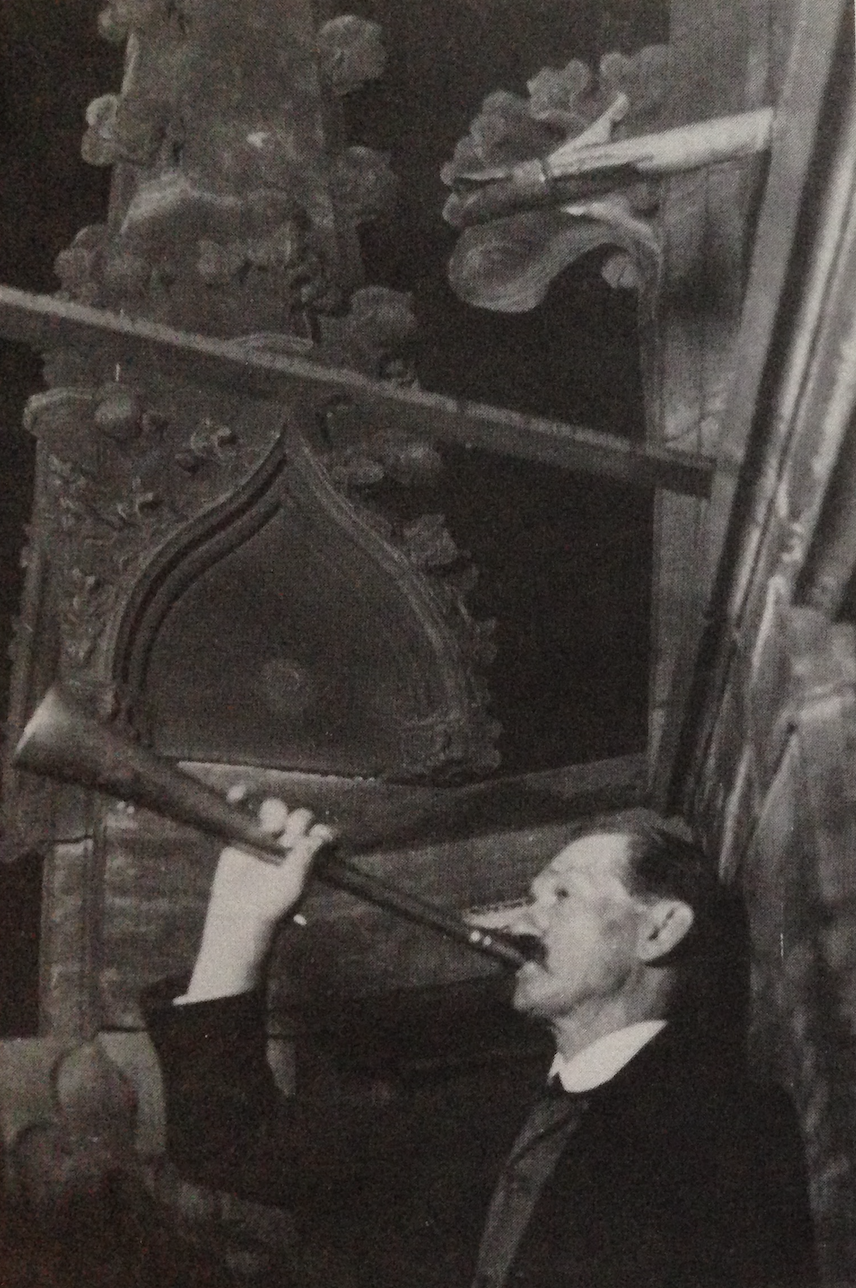 Ein Türmer mit einem kurzen Horn bläst ein Signal, er steht auf der Galerie oben auf der St. Lambertikirche in Münster.